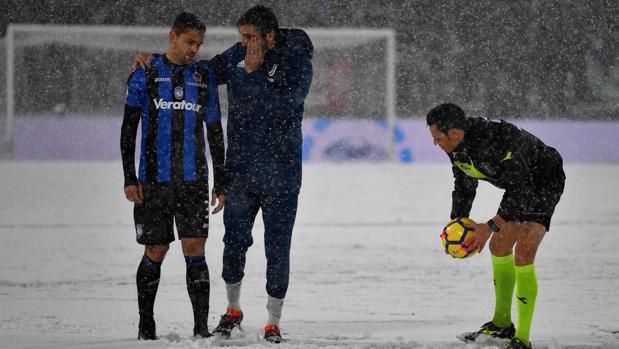 Árbitro y capitanes estudian la situación del terreno de juego