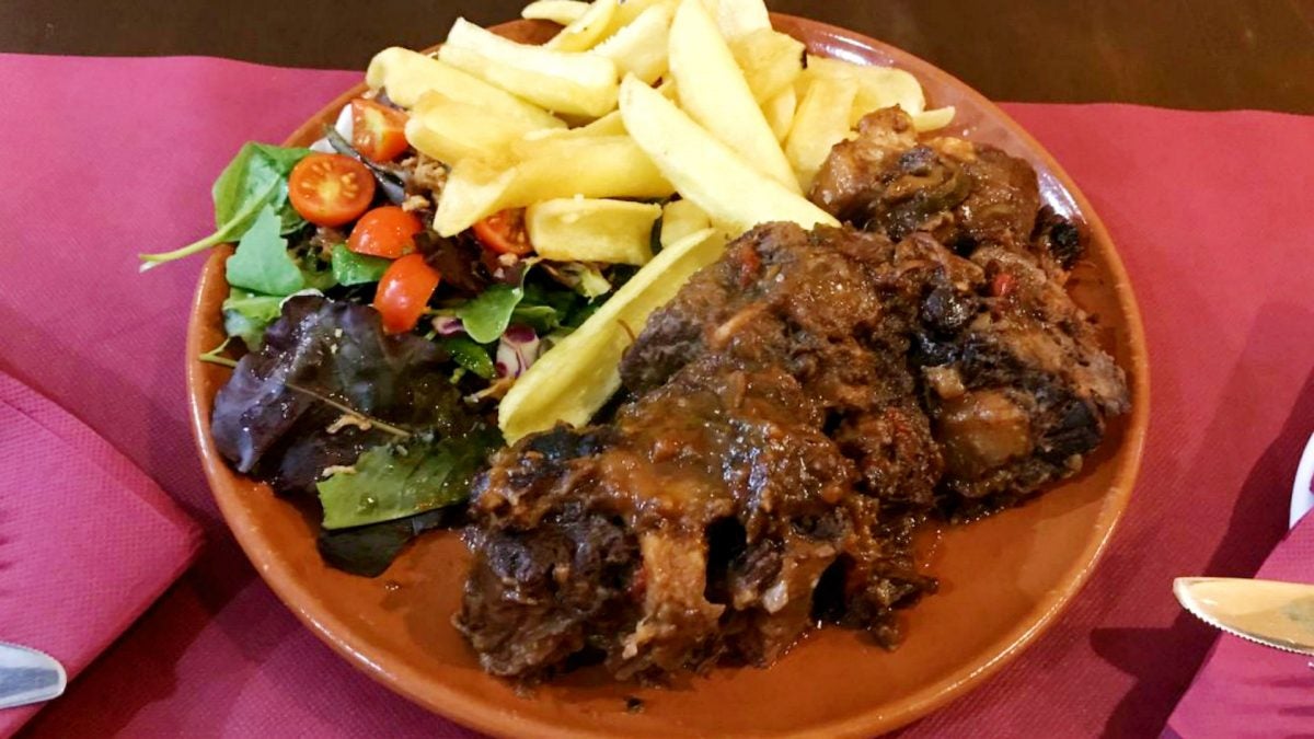 Ración de rabo de toro con verduras frescas y patatas fritas