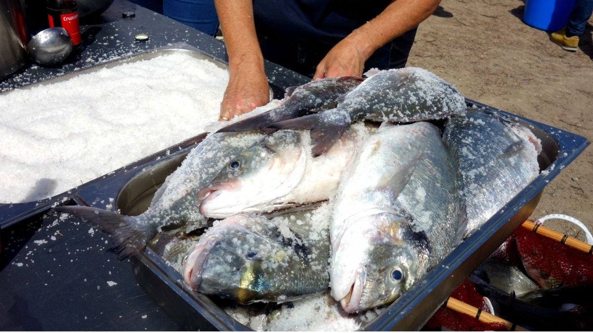 Preparando el pescado con sal para ponerlo sobre las brasas.