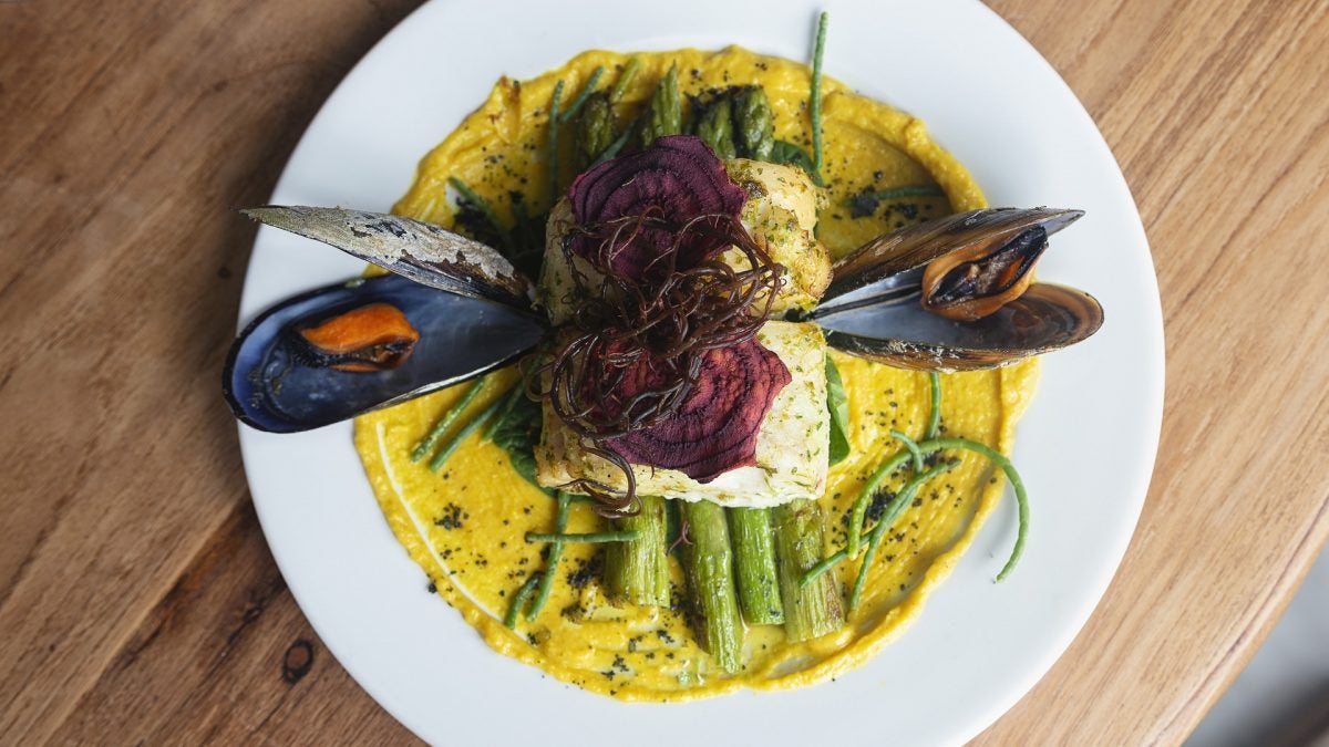 La merluza en azafrán i jengibre sobre cama de puré de coliflor con sumac, servido con espárragos, samphire y remolacha crujiente de Corredera 55.