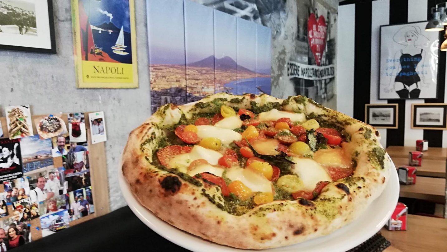 La pizza Fabrizio, con una foto de Nápoles detrás.