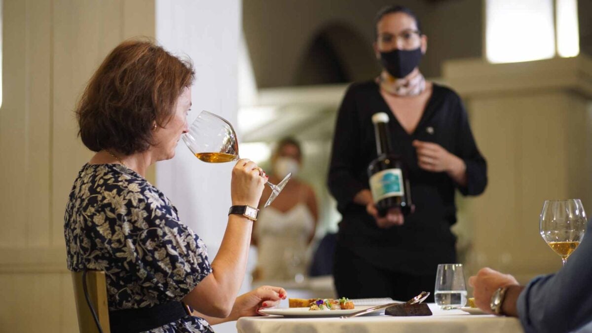 Carmen Aumesquet catando el vino que le ofrece Paula Menéndez.