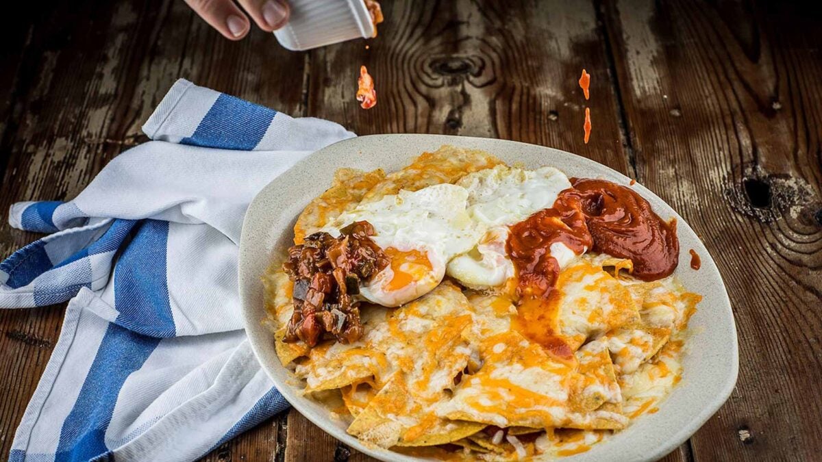 Nachos con huevos fritos, gratinados con una selección de quesos y verduras de Rota.