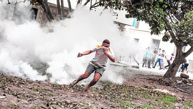Un manifestante se protege del gas lacrimógeno lanzado por las Policía marroquí