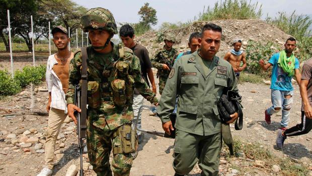 Un soldado colombiano acompaña a uno de los guardias venezolanos que abandonan a Maduro