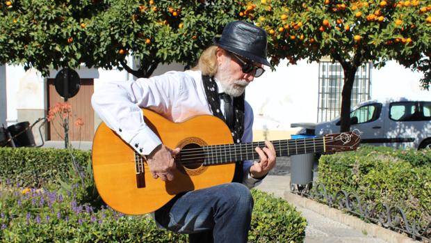 El utrerano Ramón Priego acaricia su guitarra en la plaza Enrique de la Cuadra de su localidad natal