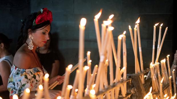Una rociera coloca una vela en el Santuario de la Virgen del Rocío